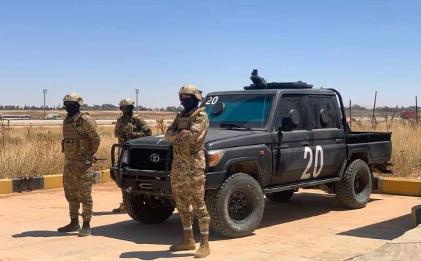 a group of people in military uniforms standing in front of a truck