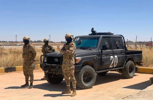 a group of people in military uniforms standing in front of a truck